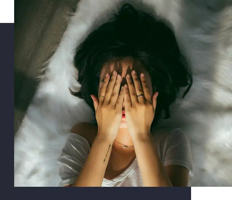 Woman lying on a faux-fur rug covering her face.