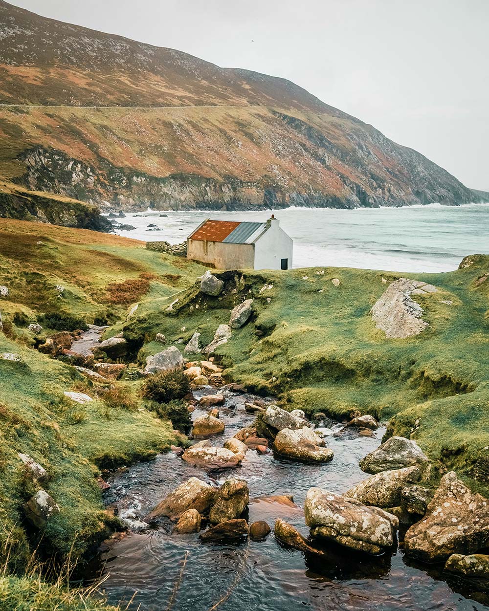 Woman in yellow pants reading a book on a window ledge.
