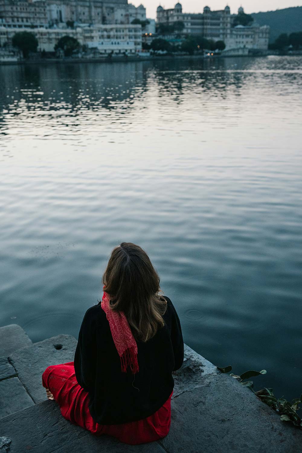 Woman in yellow pants reading a book on a window ledge.