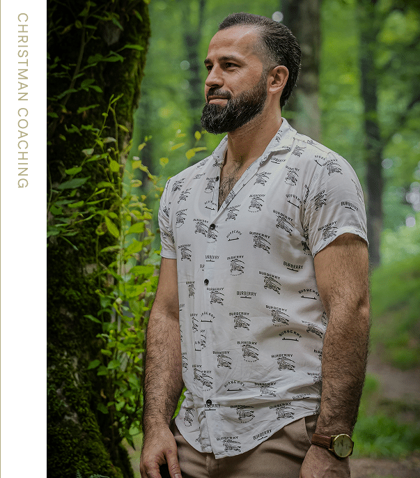 A man standing in a forest smiling, symbolizing grounding, peace, and connection to the natural environment.
