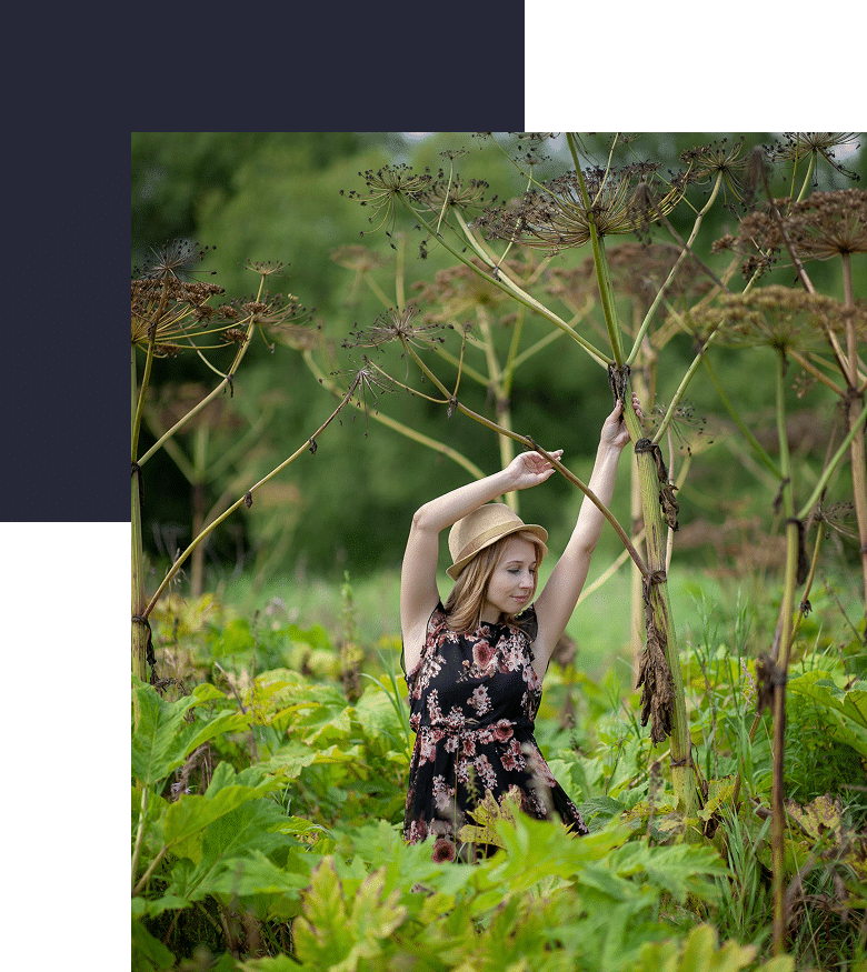 A woman in a black dress and hat is dancing in a forest, expressing freedom, joy, and emotional release through movement.